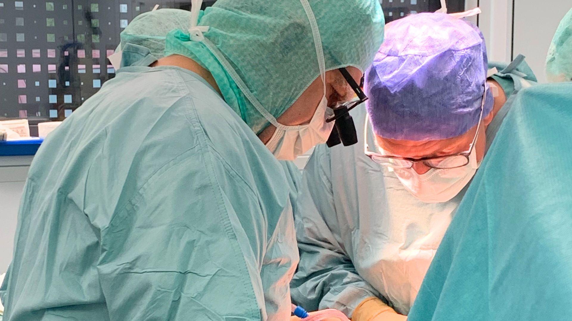 Zwei Ärzte stehe im OP-Saal am Operationstisch und operieren gemeinsam eine Patientin. Links steht PD Dr. Spiridon Botsios, Gefäßchirurg. rechts steht Dr. Marc Fischbacher, Sportorthopäde.